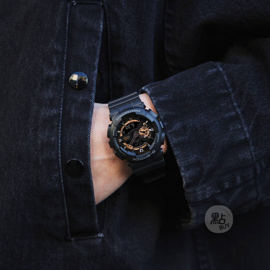 CASIO GA-110RG-1AER G-Shock 200M 防水 防震 - 手錶佩戴於手腕,深色牛仔外套袖口若隱若現