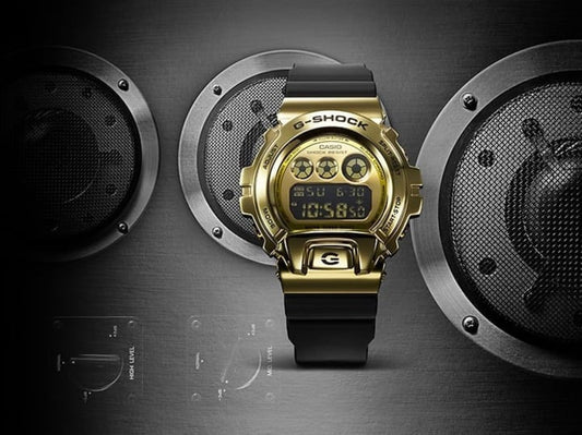 CASIO GM-6900G-9DR G-SHOCK 數碼金色錶盤男士手錶 - 金屬金色錶款，正面圖配車用喇叭背景